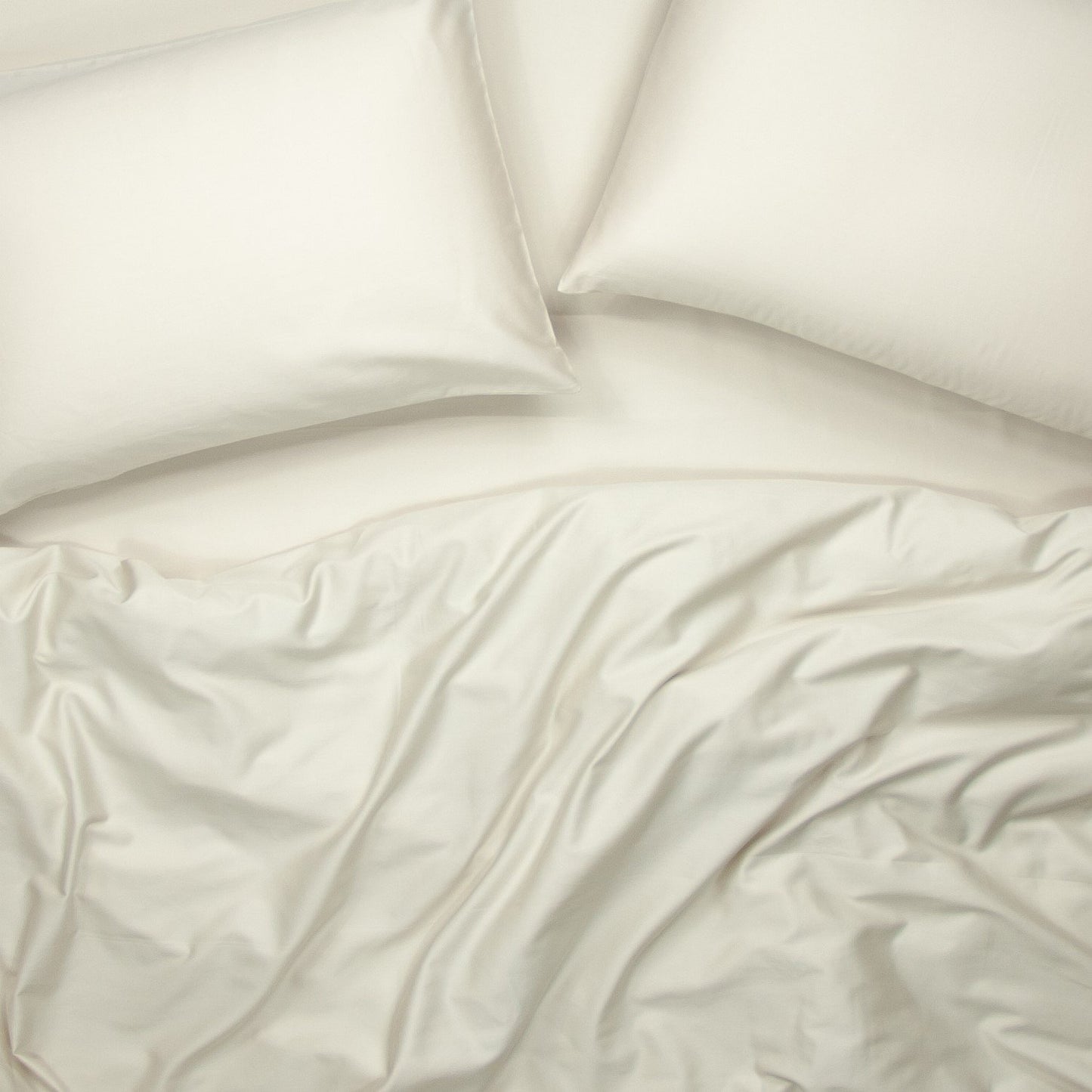 Birds eye view of organic cotton quilt cover set with pillowcases and quilt cover in egg shell white