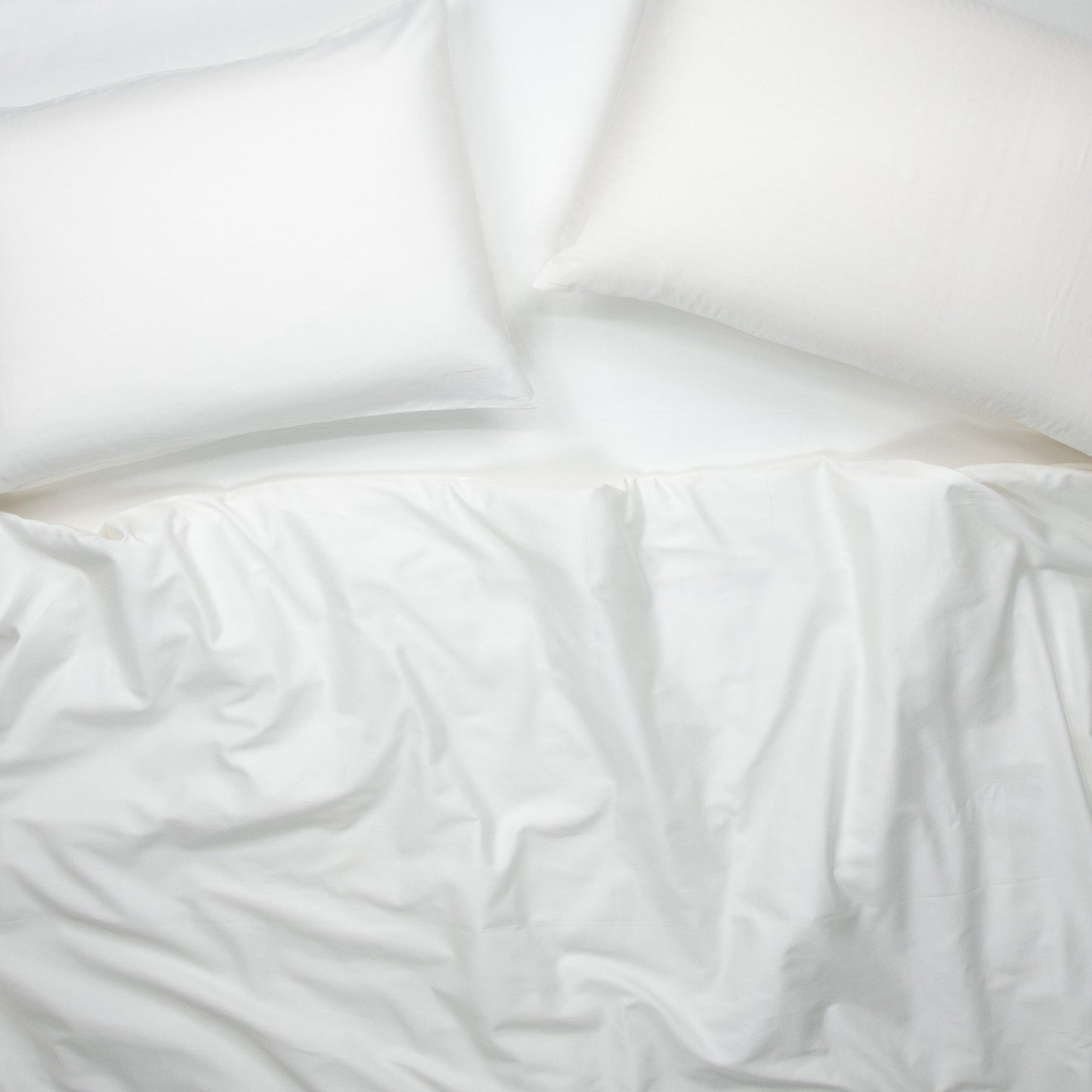 Birds eye view of organic cotton quilt cover set with pillowcases and quilt cover in pure white