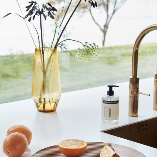 Hubsch Interior Nordic designer conical vase in gold glass sitting inside on a kitchen bench with chopped oranges