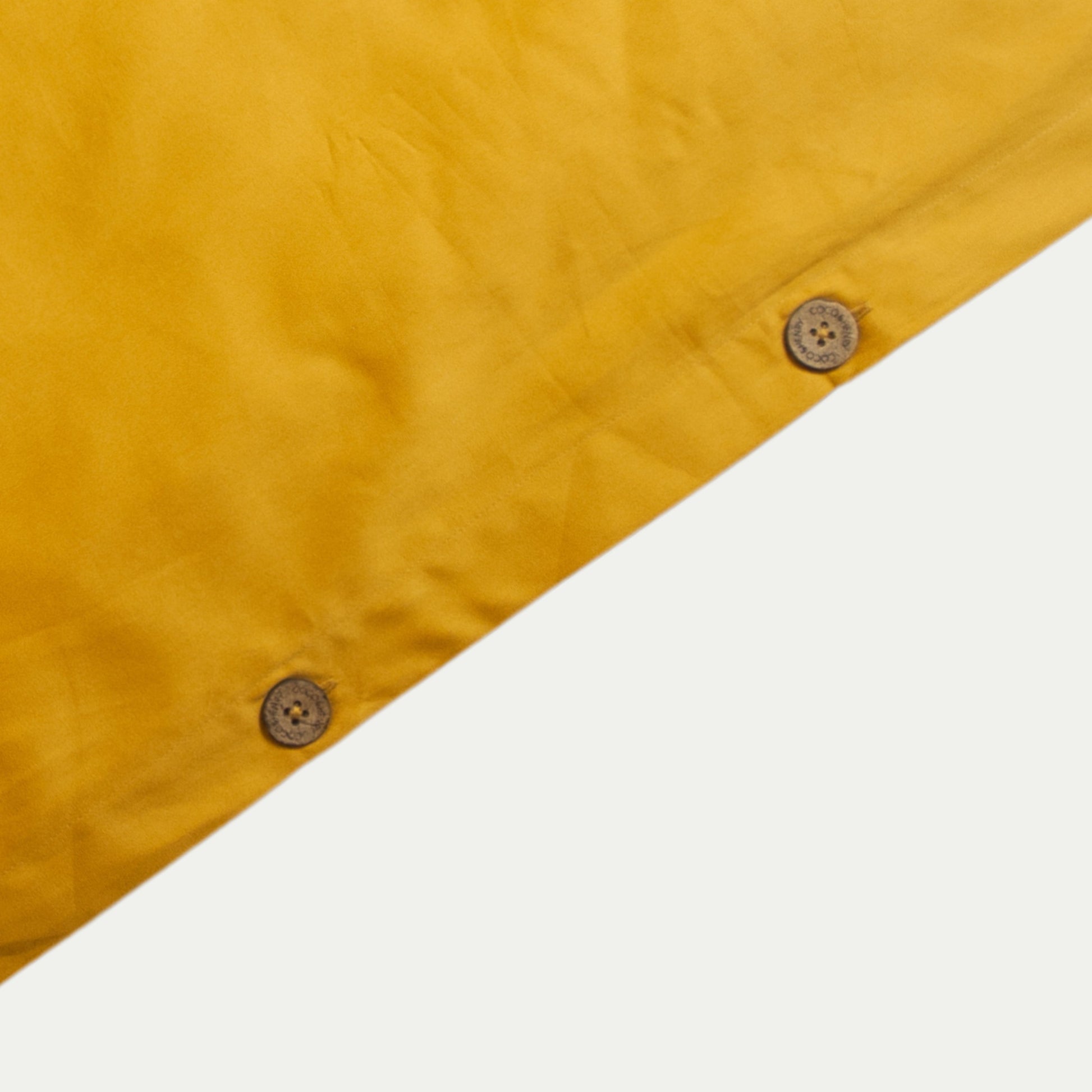 Close up of quilt cover edge with coconut buttons in honey gold