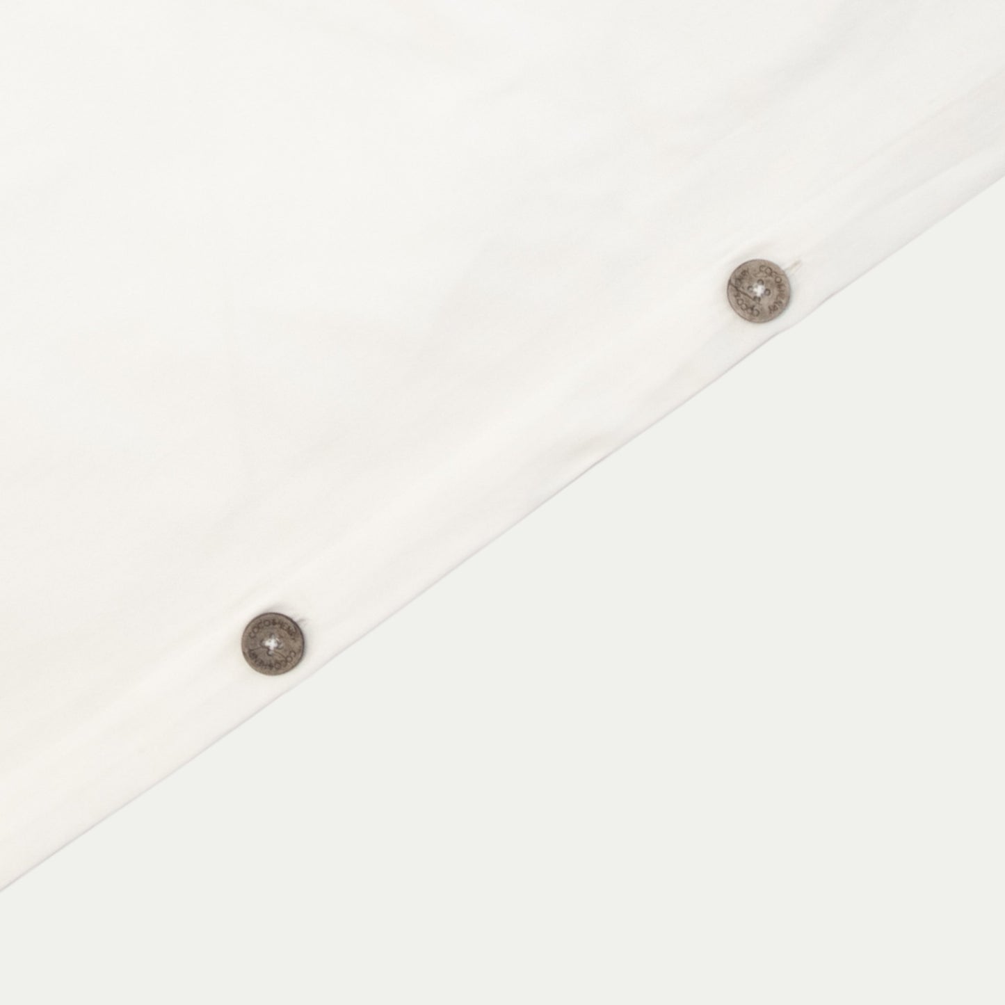 Close up of quilt cover edge with coconut buttons in warm white