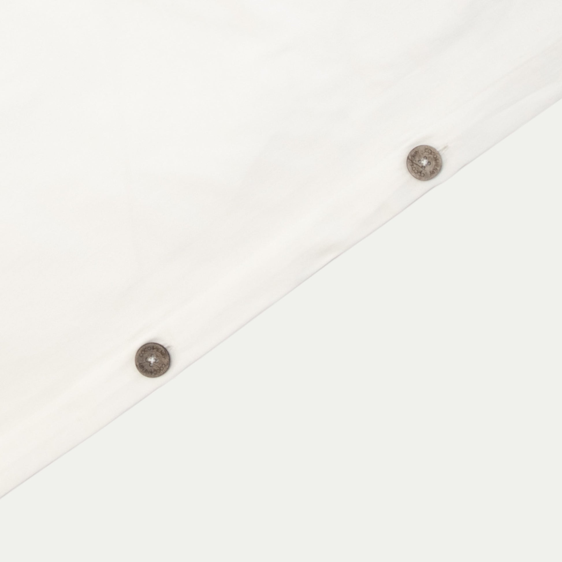 Close up of quilt cover edge with coconut buttons in warm white