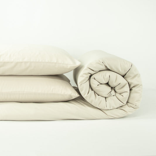 Stack of organic cotton quilt cover set with pillowcases and rolled up quilt cover in egg shell white