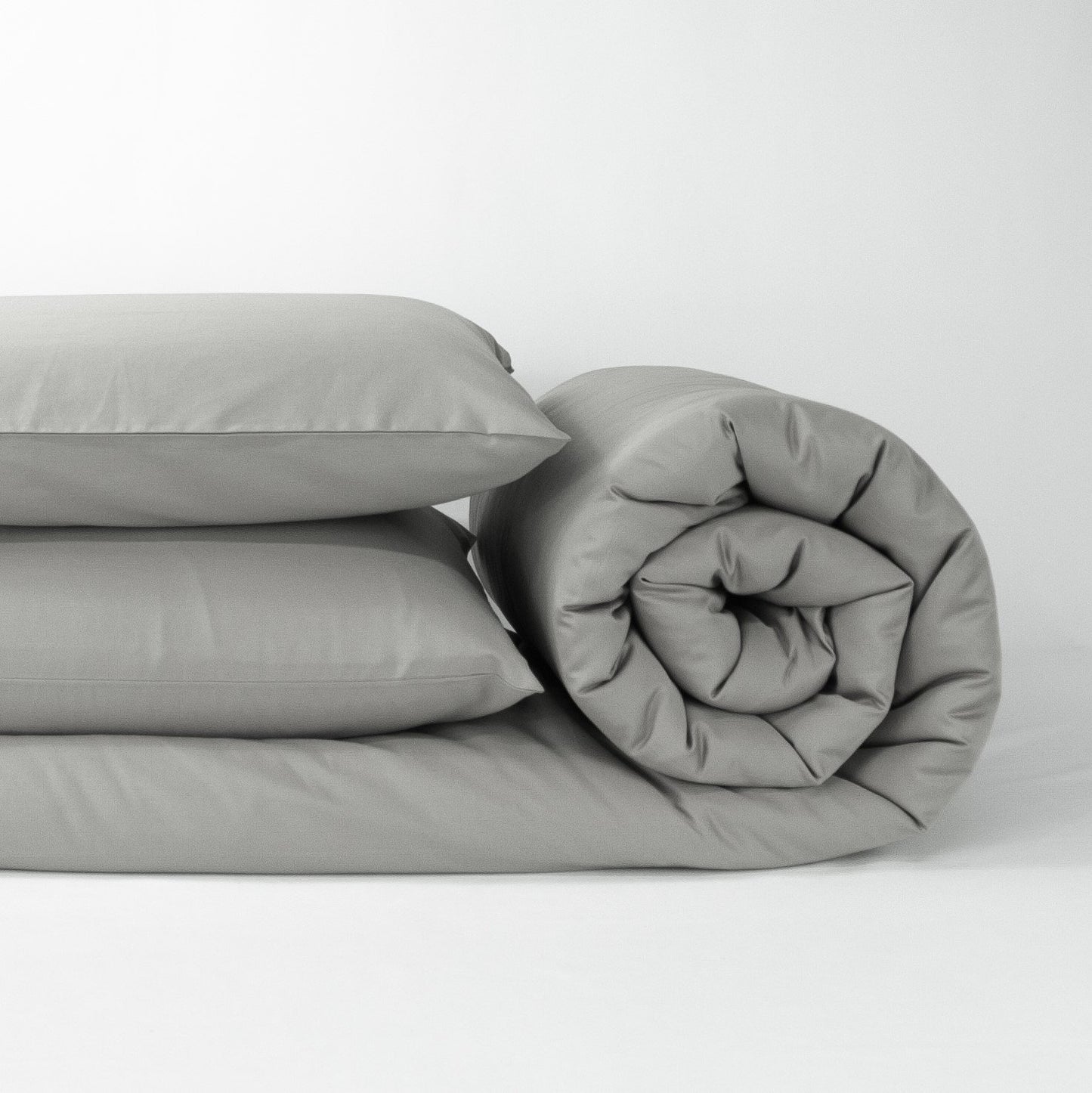 Stack of organic cotton quilt cover set with pillowcases and rolled up quilt cover in sleet grey
