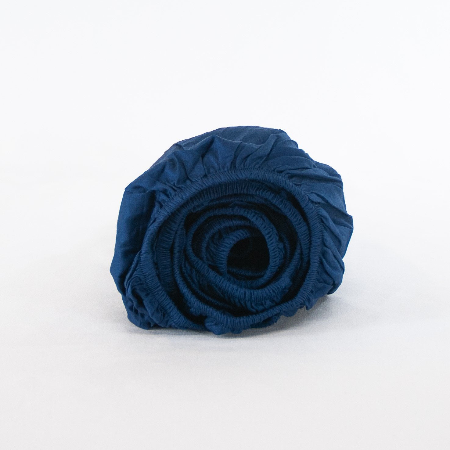 Rolled up organic cotton fitted cot sheet in classic blue