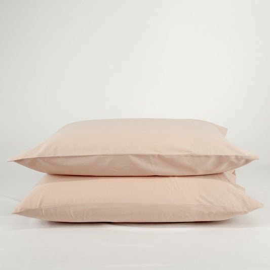 Stacked organic cotton pillowcases in blush pink