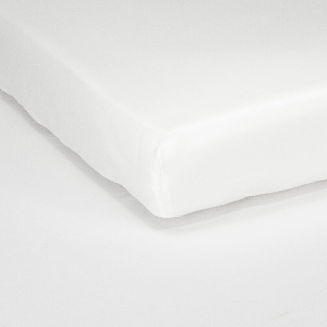 Corner of mattress with organic cotton fitted cot sheet in pure white