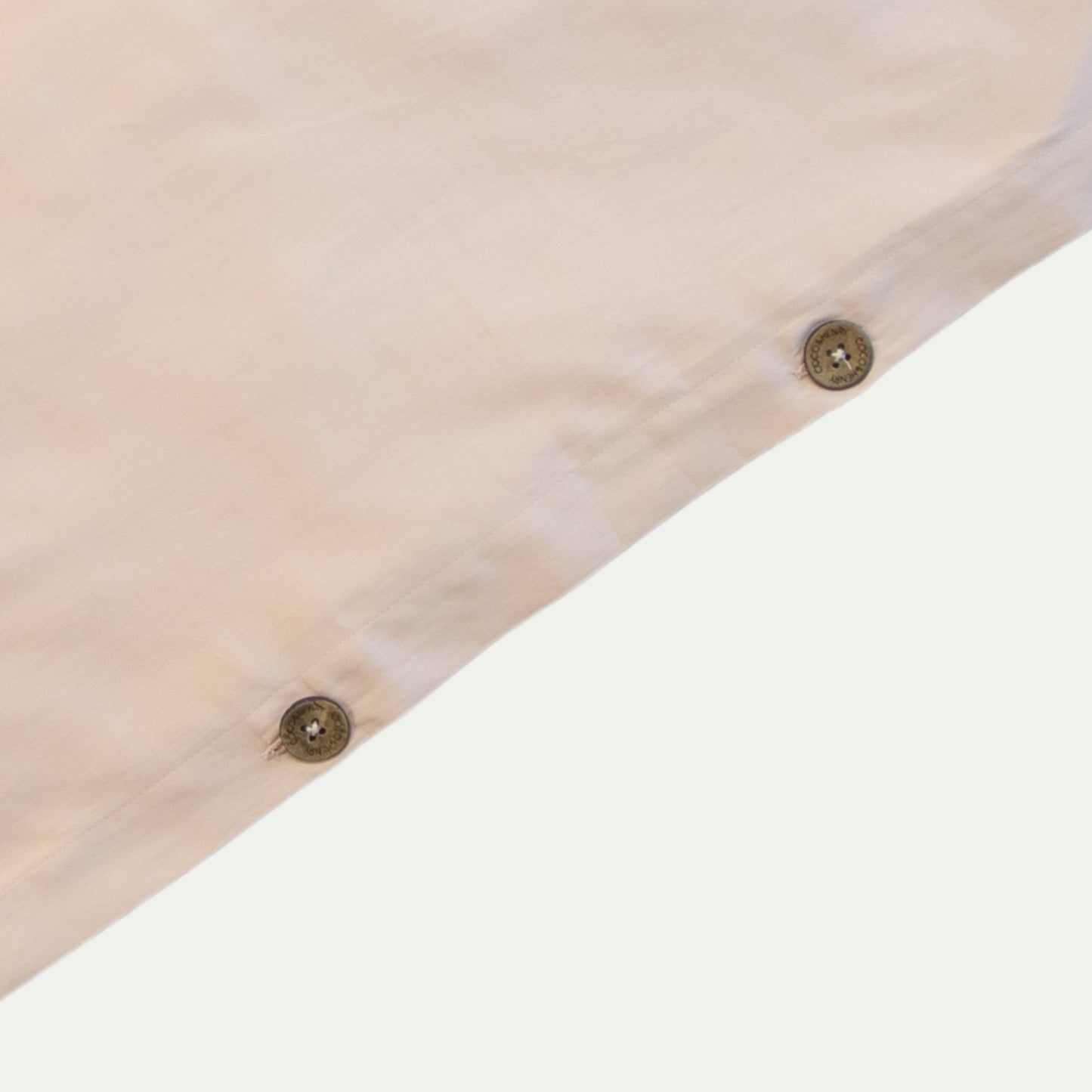 Close up of quilt cover edge with coconut buttons in blush pink