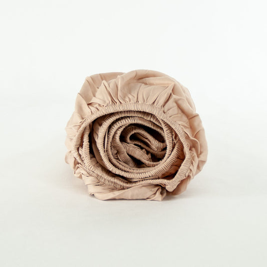 Rolled up organic cotton fitted sheet in blush pink