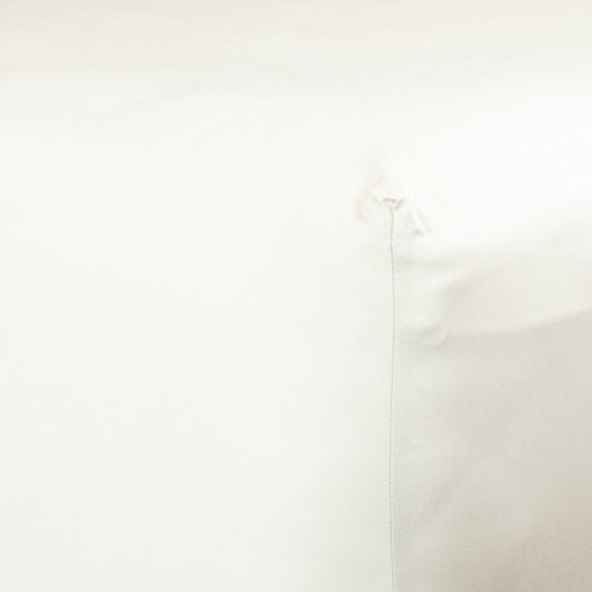 Corner of bed with organic cotton fitted sheet in warm white