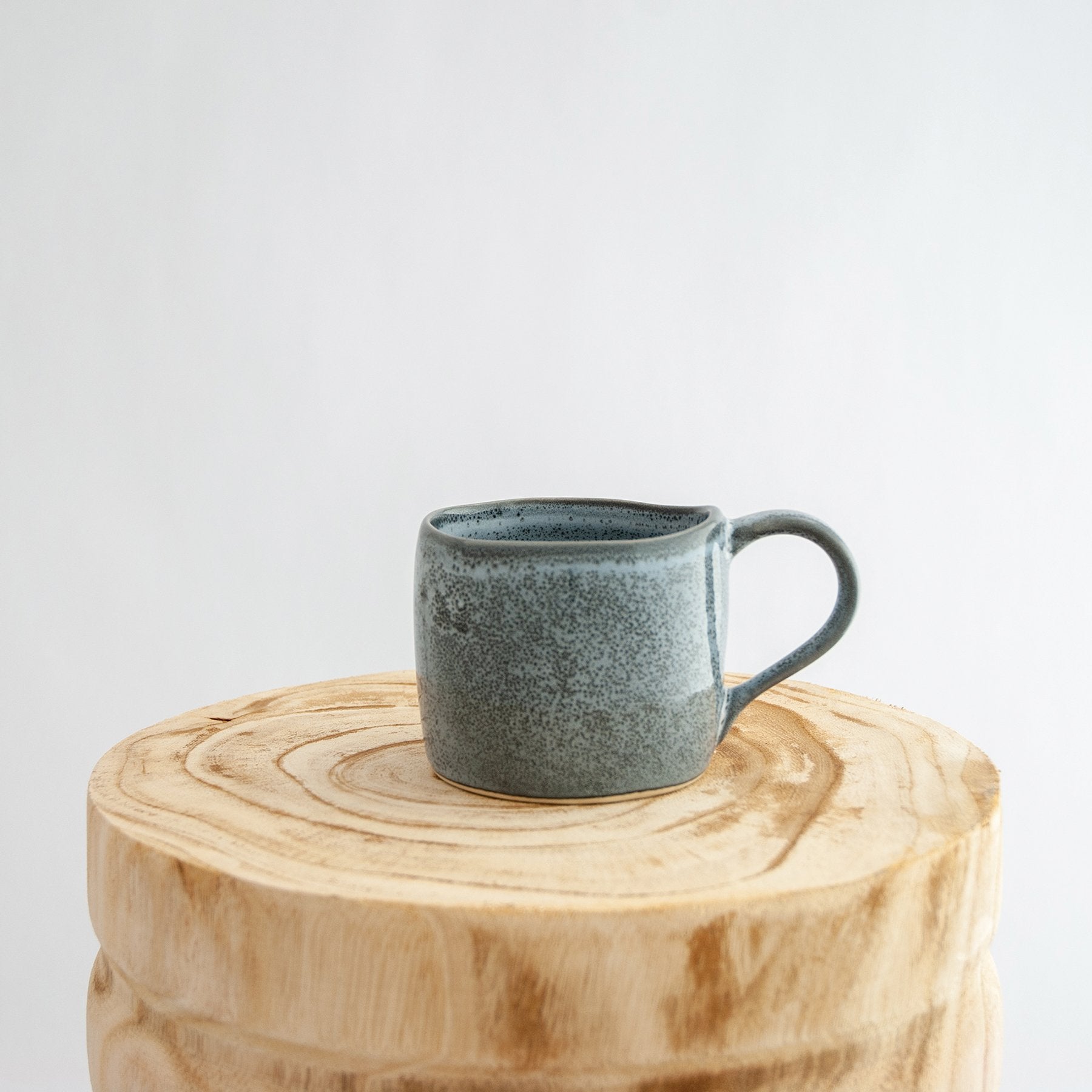 Robert Gordon storm grey organic mug coffee cup sitting on a natural wooden round side table