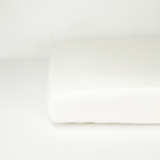 End of mattress with organic cotton fitted cot sheet in warm white
